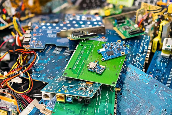 A pile of assorted electronic circuit boards and components, including wires, chips, ports, and various connectors.